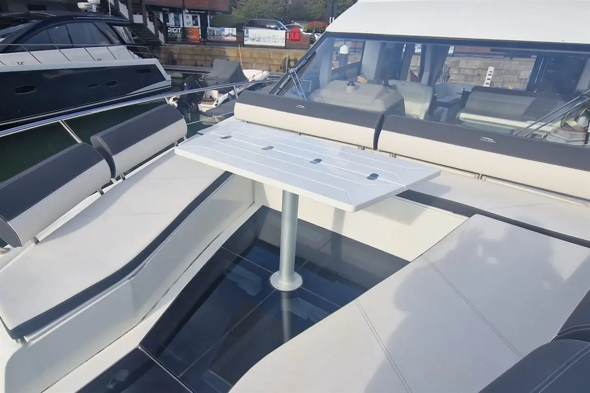 Boat deck with a retractable table, leather seating and a spacious layout, showcasing a modern marine design aesthetic.
